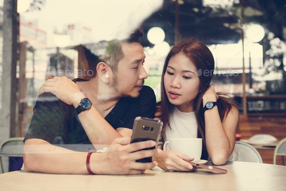 Couple using a phone at a cafe - Stock Photo - Images