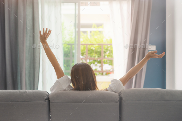 Young woman relaxing on sofa at cozy home and looking outside in living room - Stock Photo - Images