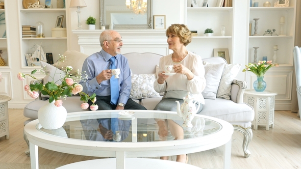 Happy Caucasian Couple of Retirement Age Are Spending Time Together Sitting at a Table and Drinking alt