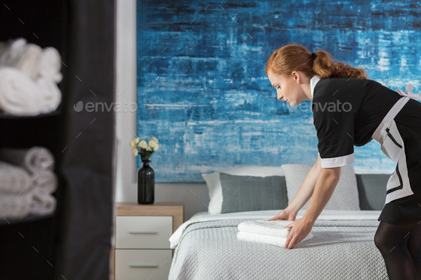 Maid laying towels on bed - Stock Photo - Images