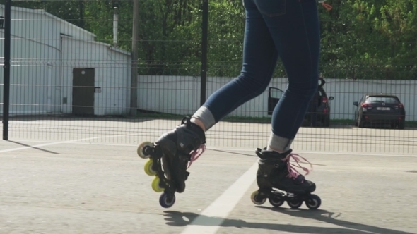 Women's Legs in Roller Skates Ride on Asphalt Road