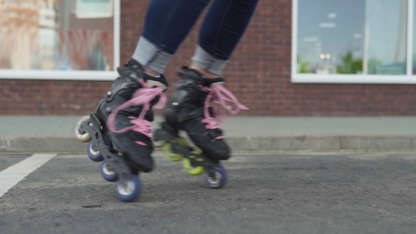 Women's Legs in Roller Skates Whirl Around on Asphalt in City