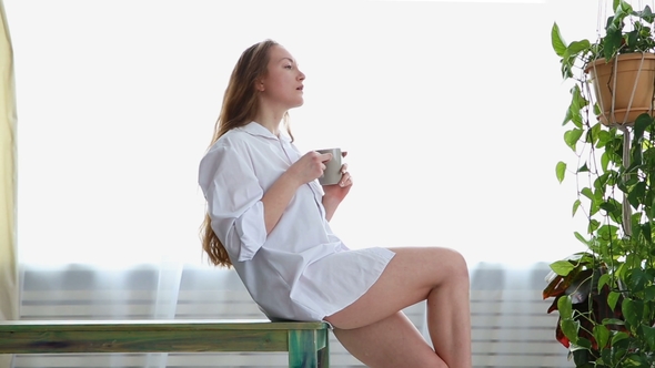 Woman in White Man's Shirt Drinking Coffee at Home