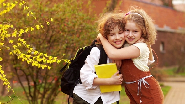 Schoolchildren, Brother and Sister, Boy and Girl Hug Against the Background of a Blossoming Spring alt