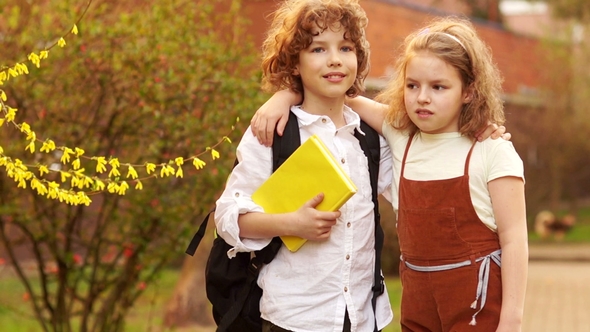 Boy and a Girl Hugging Each Other against Background of a Blossoming Spring Tree alt