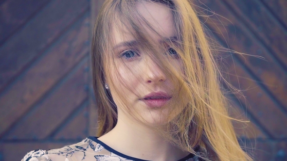 Girl with Long Wheat-colored Hair. Looks Directly Into the Camera, the Hair Develops the Wind