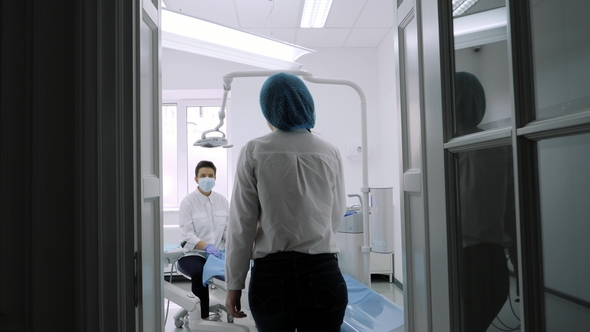 Dentist Invites Patient To Sit Down Patient Sits Down on Blue Dentist Chair. alt