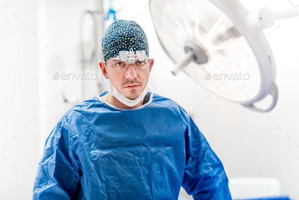 Portrait of surgeon with sterile equipment and surgery lamps working in hospital operating room.