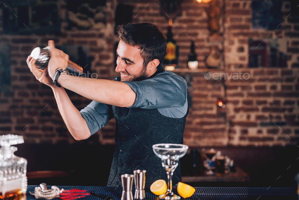 barman using shaker for cocktail preparation. Portrait of barman making  tequila based margarita Stock Photo by stockcentral