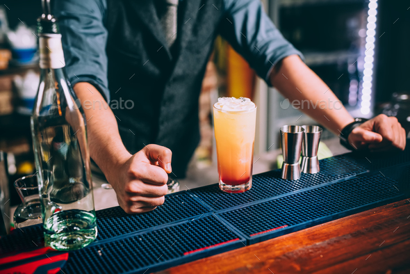 Portrait of elegant and vintage bartender, barman preparing orange based vodka and tequila cocktails Stock Photo by stockcentral