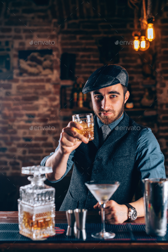 Barman enjoying whiskey with modern urban cocktails. Sky bar serving elegant drinks