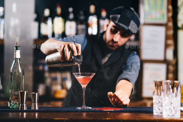 Portrait of vintage barman workin in bar. Pouring and preparing cocktails Stock Photo by stockcentral