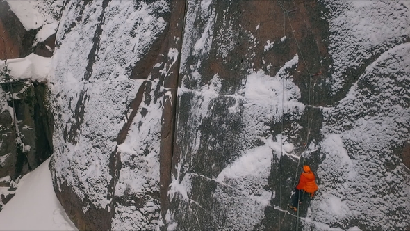 Aerial View of a Rock Climber Climbing a Steep Cliffs During a Sunny Winter Day