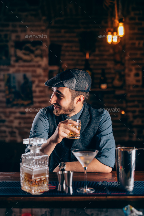 Cheerful bartender enjoying an alcoholic drink at pub, bar or restaurant. Evening relaxation concept Stock Photo by stockcentral