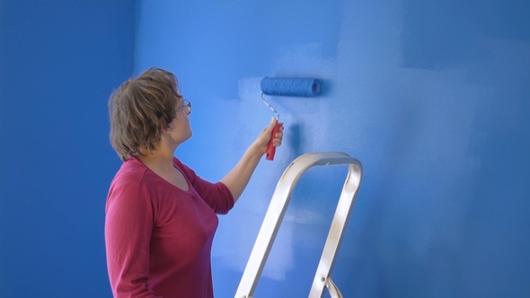 Adult Woman Painting Interior Wall of House with Blue Paint
