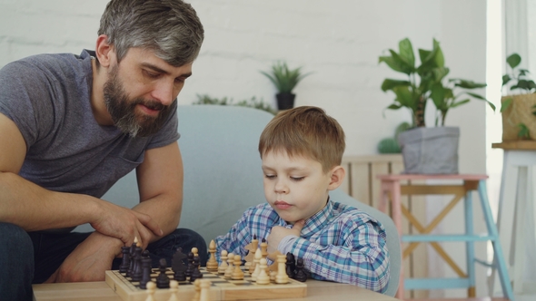 Serious Preschool Child Is Playing Chess with His Parent Thinking About Next Move and Moving alt