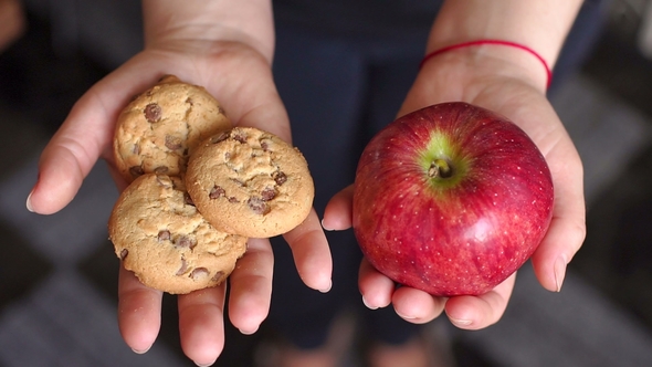 The Girl Is Holding an Apple and Cookies,