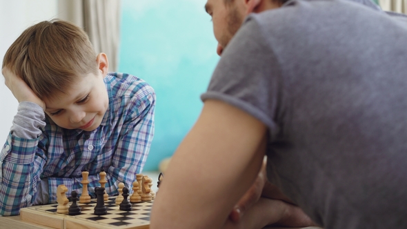 Father and Son Playing Chess, Thinking About Next Move alt
