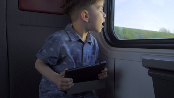 Boy Riding in the Train Playing Games on the Tablet