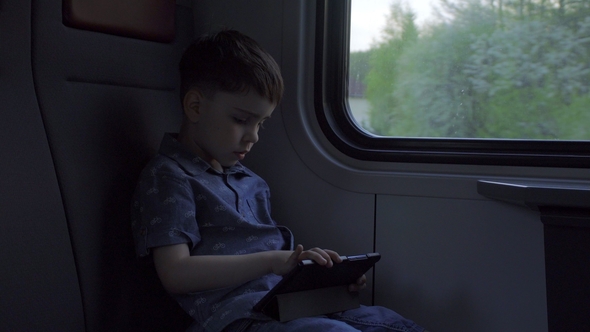 The Boy Is Riding in the Train, Playing Games on the Tablet