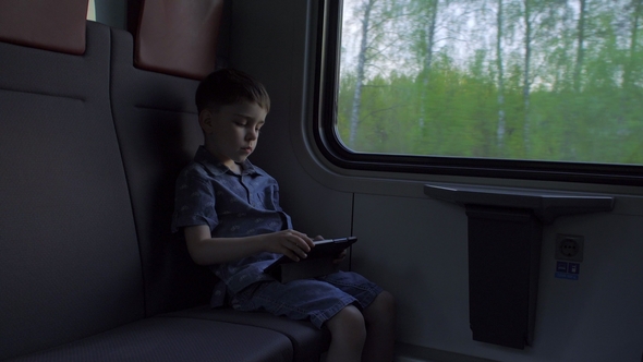 The Boy Is Riding in the Train, Playing Games on the Tablet