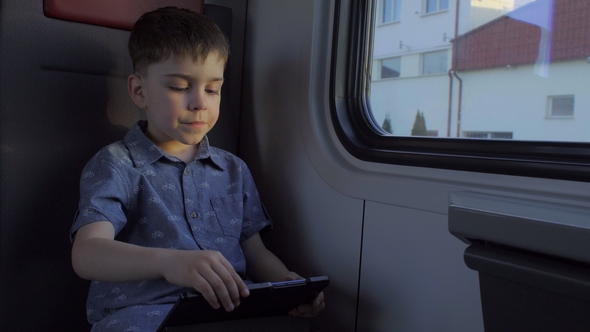 The Boy Is Riding in the Train, Playing Games on the Tablet