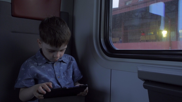 The Boy Is Riding in the Train, Playing Games on the Tablet