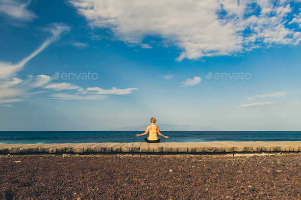Yoga girl meditating and relaxing in yoga pose, ocean view Stock Photo by blas