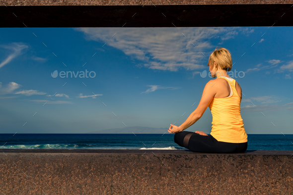 Yoga girl meditating and relaxing in yoga pose, ocean view Stock Photo by blas