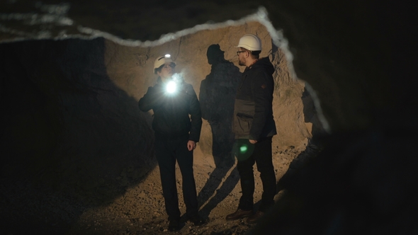 Two Speleologists with Flashlight Exploring the Cave with Fear in Darkness alt