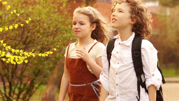 The Spring Wind Breaks the Petals From the Blooming Trees. Children, Schoolchildren, Boy and Girl alt