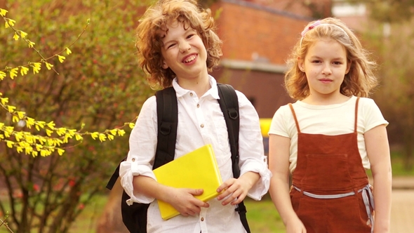 Brother and Sister, Schoolchildren, Boy and Girl Hug Against the Background of a Blossoming Spring alt