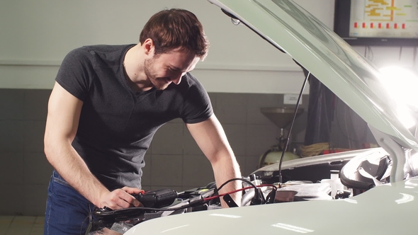 Young Technician Man Making Engine Service of Car in Garage. alt