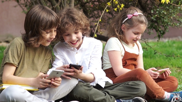 Schoolchildren Play Games on Smartphones during a School Break alt