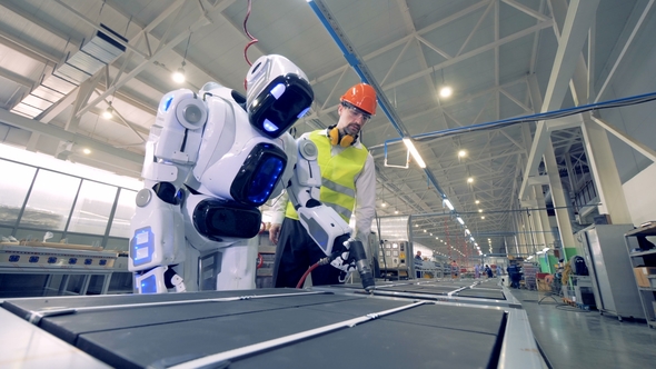 Factory Worker Is Regulating Robot's Settings By Remote Control During Working Process alt