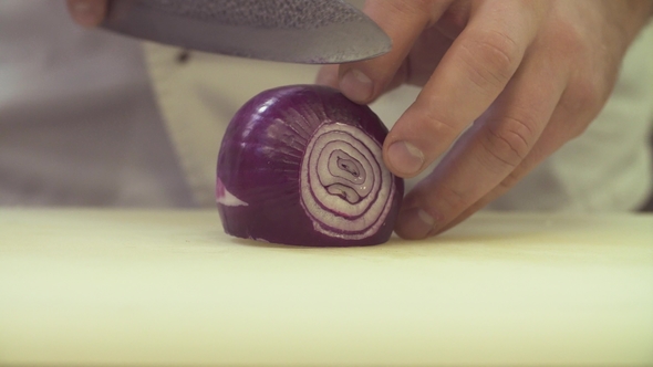 Hands of Chef Cutting Up Onion with a Knife