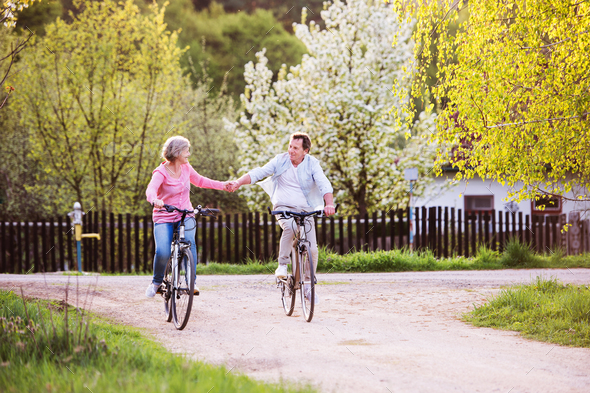Beautiful senior couple with bicycles outside in spring nature. Stock Photo by halfpoint
