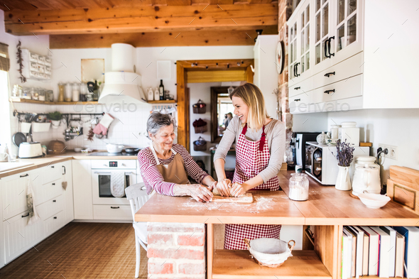 An elderly grandmother with an adult granddaughter at home, baking. - Stock Photo - Images