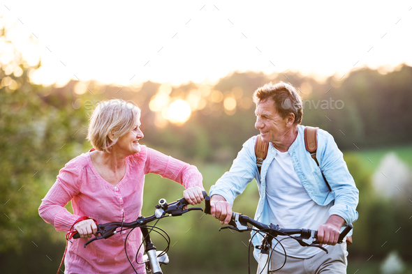 Beautiful senior couple with bicycles outside in spring nature. Stock Photo by halfpoint