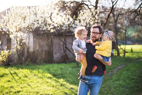 A father with toddler children outside in spring nature. - Stock Photo - Images