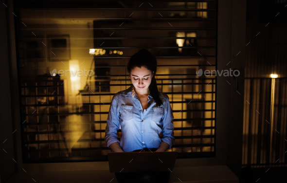 A woman working on a laptop at home or in the office at night. Stock Photo by halfpoint