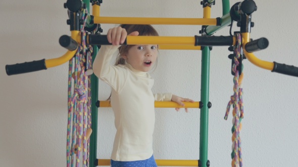 Little Girl Climbing up on Wall Bars