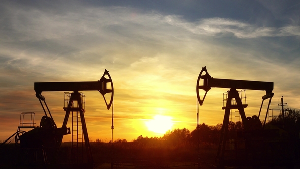 Working Oil Pumps Silhouette Against Sunset alt