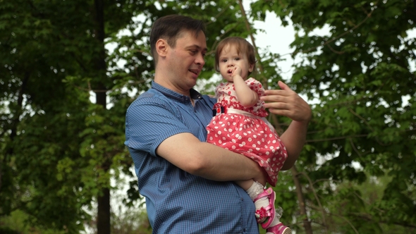 Parent with Child Waving His Hand and Smiling in Green Park alt