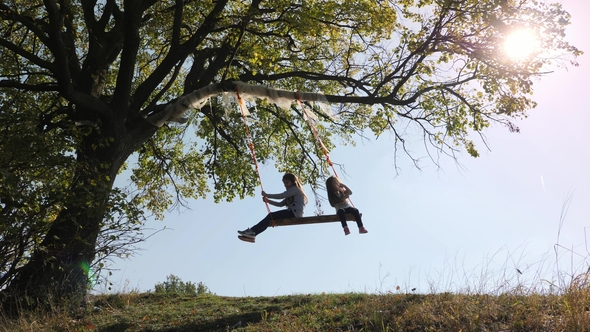 two girls swinging on