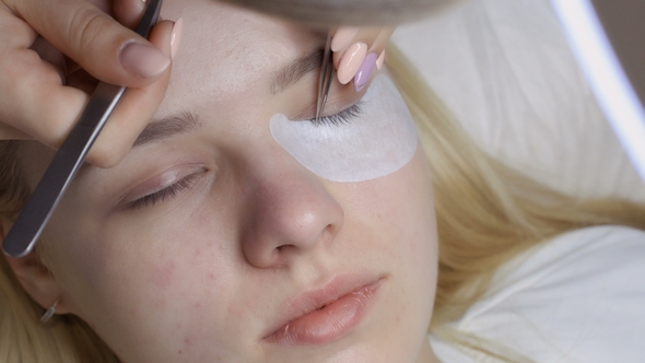 Beautician Makes Eyelash Extension To Young Blonde in Beauty Salon, alt