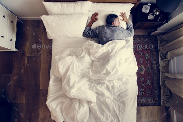 French man sleeping alone on bed