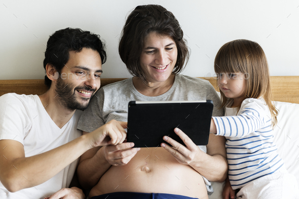 Pregnant family spending time together using a digital tablet - Stock Photo - Images