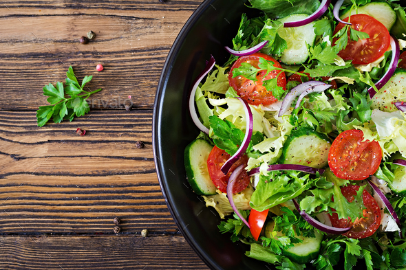 Salad from tomatoes, cucumber, red onions and lettuce leaves. - Stock Photo - Images