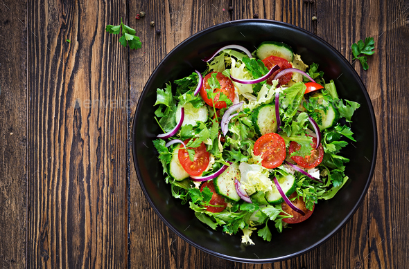 Salad from tomatoes, cucumber, red onions and lettuce leaves. - Stock Photo - Images